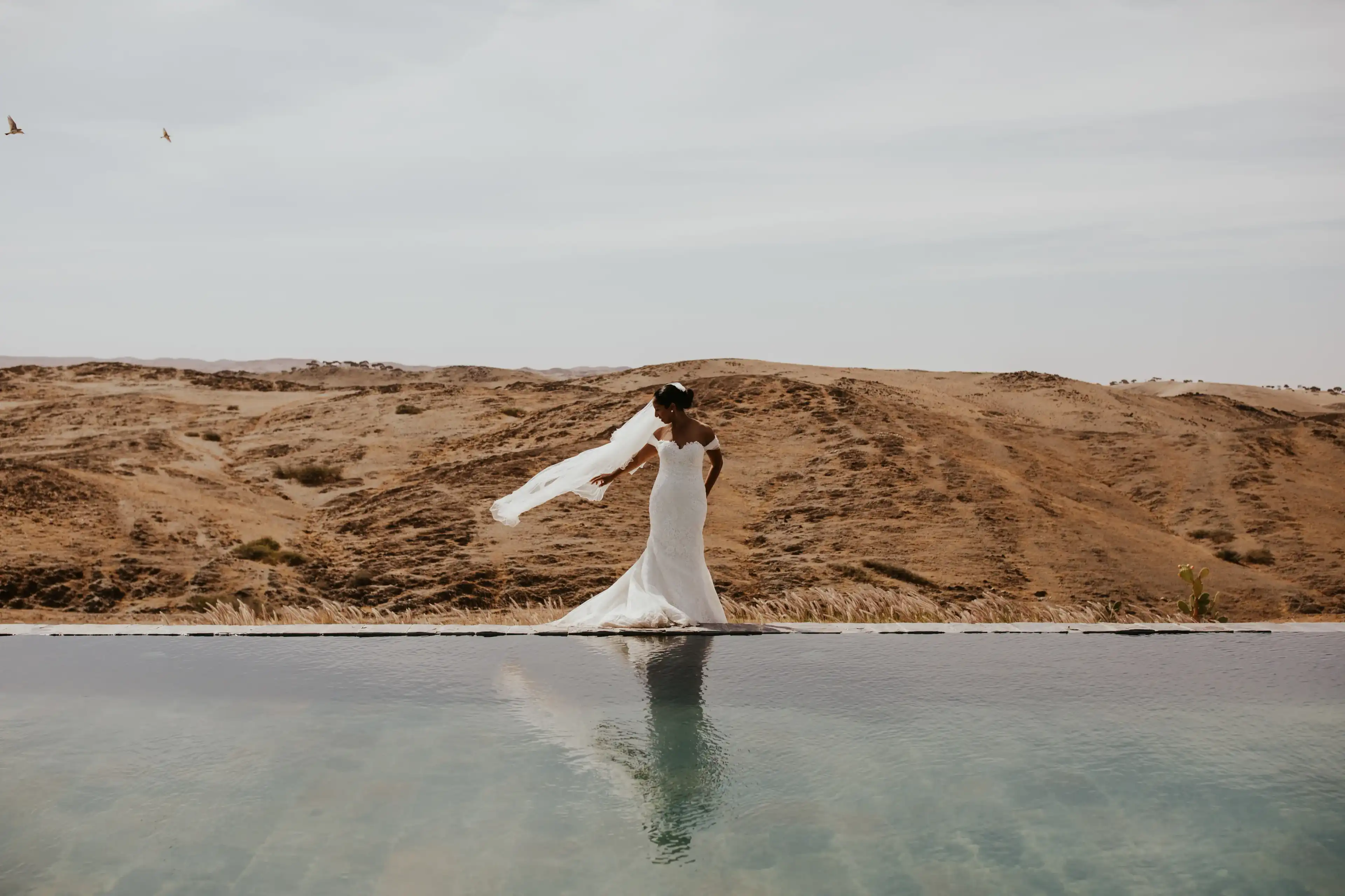Photo shoot : une mariée pose devant une piscine dans le désert près de Marrakech