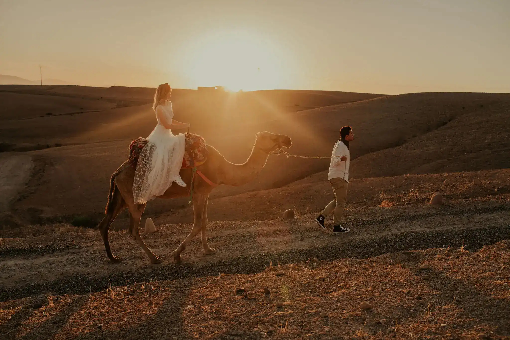 Couple elopement in Moroccan desert, doing a camel ride at sunset
